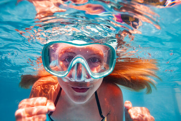 Beautiful underwater close-up portrait of the smiling little girl with long hairs wearing scuba mask