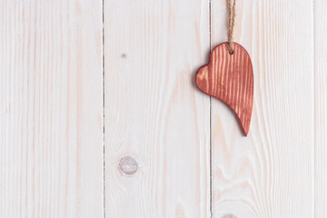 Wooden heart on a white rough wooden background.