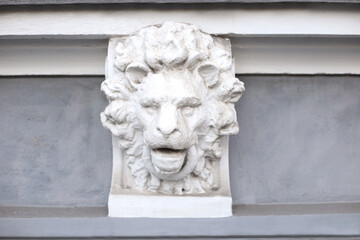 Fototapeta premium White sculpture of a lion's head on the grey building's facade