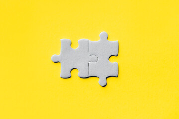 Obraz premium Closeup of jigsaw puzzle piece. Demonstrating trendy Color of Year 2021. Illuminating Yellow and Ultimate Gray. Duotone. Puzzle pieces on yellow background. idea, sign, symbol, concept of connecting