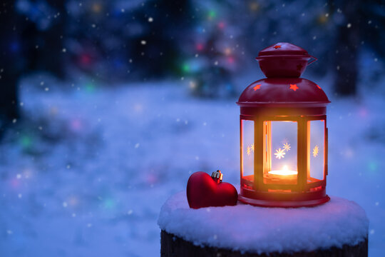 Christmas light with heart toy in winter forest. New year's lantern illuminates the winter forest