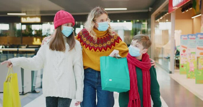 Beautiful young happy family with young brither and sister kids walking at large modern market shopping for Christmas holiday presents. Quarantine concept.
