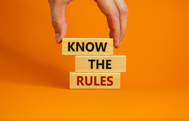 Know the rules symbol. Wooden blocks with words 'know the rules'. Male hand. Beautiful orange background. Copy space. Business and know the rules concept. - obrazy, fototapety, plakaty