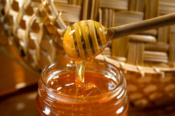 Fototapeta na wymiar Honey drips from the honey bucket into the jar. Close-up. Healthy organic thick honey