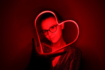 Valentine day. Beautiful girl with neon signs. Neon sign red heart. Party concept. Modern style....