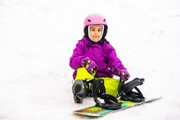 Little Cute Girl Snowboarding at ski resort in sunny winter day.