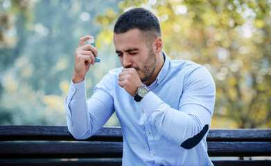 Young man treating asthma with inhaler. Health care concept