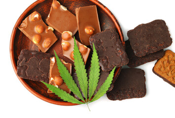 Edible cannabis from marijuana leaf with CBD content and edible chocolate on white isolated background. Hemp leaf and chocolate-coated cookies