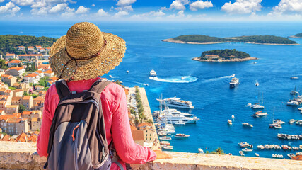 Coastal summer landscape with a tourist girl resting - top view of the City Harbour and marina of the town of Hvar from the fortress, on the island of Hvar, the Adriatic coast of Croatia - obrazy, fototapety, plakaty