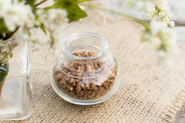 Obraz na płótnie Canvas Transparent jar for loose products with dry buckwheat.