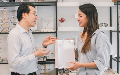 Asian female customer buying eyeglass at store