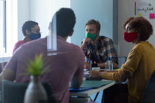 Diverse group of colleagues wearing face masks in office meeting