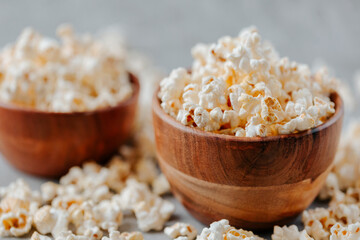 Homemade popcorn in a wooden bowl on a grey background