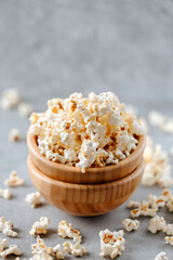 Popcorn in a wooden bowl on a grey background