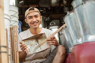 smiling craftsman holding a dustpan trash when showing to the camera in the household appliances store