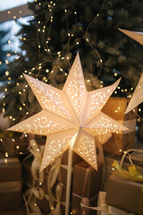 Beautiful Christmas tree with presents by the big window. Winter is coming. Plaid with pillows on windowsill. Big shining stasr.