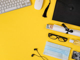 A square academic cap, keyboard, mask, headphones, mouse, disinfectant and certificate with money are located in a semicircle on the right on a yellow background with space for text on the left, top v