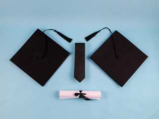 Two graduation caps, a tie and a certificate on a blue background, close-up top view.