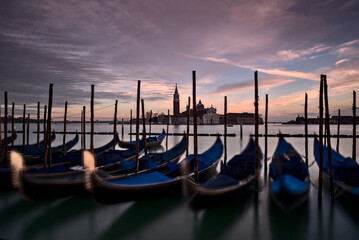 Venezia, gondole in piazza San Marco con sullo sfondo la chiesa di San Giorgio maggiore illuminata dal tramonto © Massimiliano