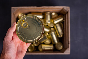 Metal food cans Held in a male hand. Food stockpiled for hard times.
