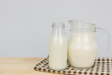  A jug and bottle of milk glass on a wooden table on background..Raw milk is high in calcium and protein to drink for all ages..Milk consumption nutritious and healthy dairy products concept..