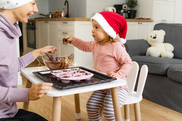 Mother with child preparing holiday cookies at home. Happy family time together