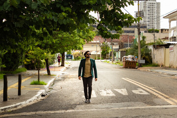 Fototapeta na wymiar Homem elegante, usando óculos de sol e blazer, caminhando na rua.