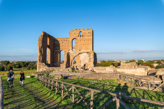 Villa dei Quintili, Rome, remains of the thermal baths, the caldarium Via Appia, on a day of blue sky a suggestive panoramic image of the brick building with tourists and the shadows of the fence. 