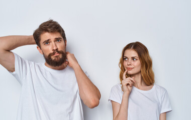 Naklejka premium A beautiful woman and a young man in identical T-shirts on a light background are gesturing with their hands