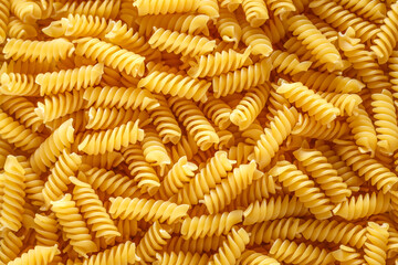 Dry pasta fusilli. Fusilli have spiral shape and yellow color. Pasta is delicious Italian traditional food made from wheat flour like noodles.Pasta background.Top view