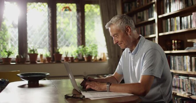 4k, Portrait of a happy and cheerful senior businessman using laptop at home