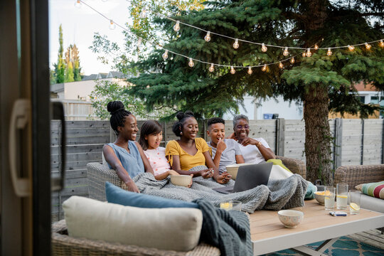 Family Watching Movie On Laptop In Backyard