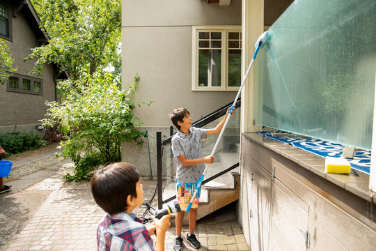 Boys Cleaning Glass Wall On House Exterior