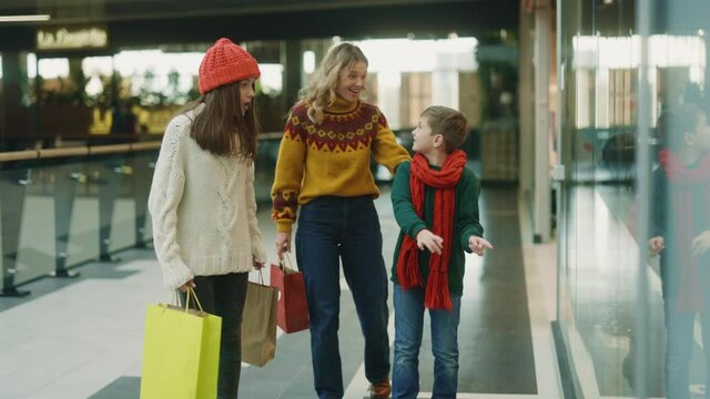 Caucasian happy gorgeous family shopping at retail store during holidays. Funny cute little boy begging for fnew shoes on his knees. Humor concept.
