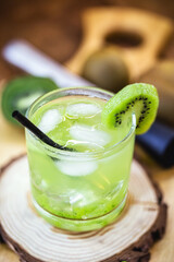 Cold drink with kiwi in a glass on wooden background. Drink called mojito or caipirinha