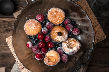 Frozen cherries, mountain ash and plums with frost in a transparent brown plate on a wooden...
