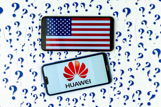 HUAWEI logo and American flag on the smartphones and a lot of cut paper question marks around. The conceptual photo about future of HUAWEI in the US.