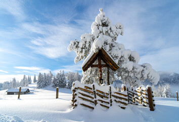 Holzkreuz im verschneiter Berglandschaft im Winter