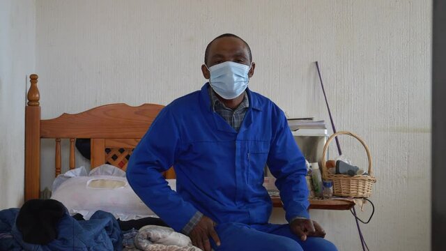 Black African male putting on a facemask before starting his days work to avoid contracting Covid-19 Coronavirus in South Africa