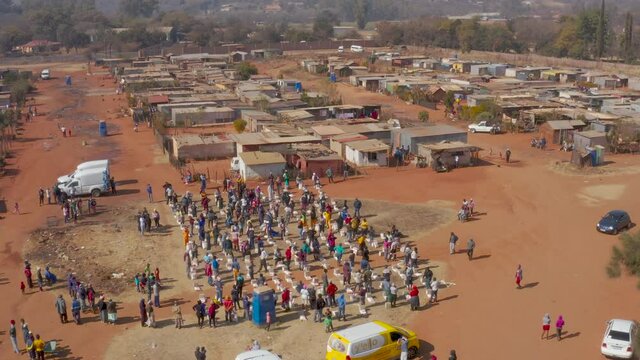 AFRICA,SOUTH AFRICA,CIRCA 2020.  Aerial view of Black African people social distancing receiving food parcels in a poverty stricken informal settlement during lockdown, Covid-19 Coronavirus pandemic