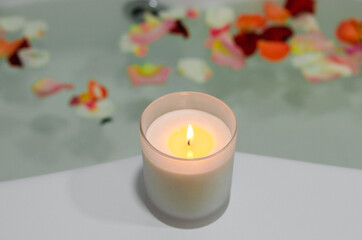 a relaxing candle and rose petals in a bathroom