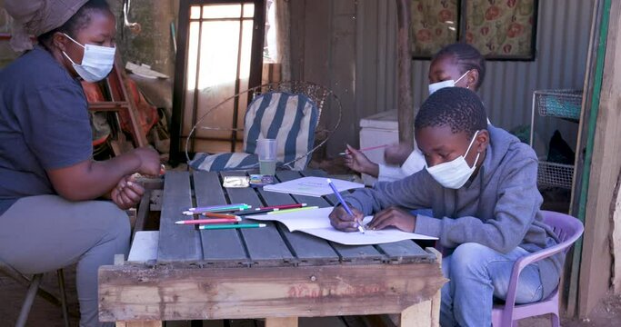 Black African woman home schooling her two young children at their dilapidated home during lockdown for Covid-19 Coronavirus pandemic, South Africa