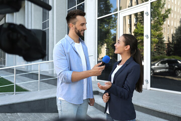 Professional journalist taking interview in front of video camera outdoors