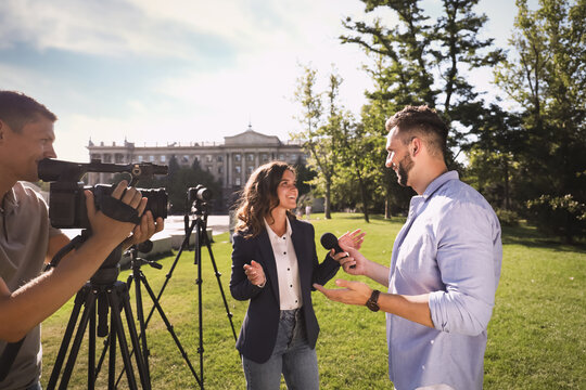 Professional journalist and operator with video camera taking interview outdoors