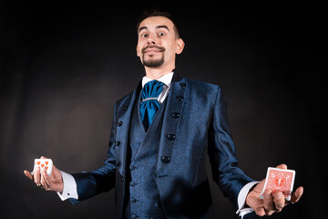 A magician with a surprised look in a blue tailcoat on a black background holds cards in his hands