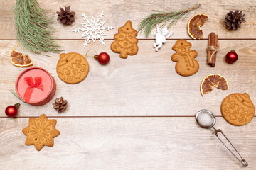 Frame of different delicious christmas gingerbread cookies, decorations, spices on wooden background, flat lay. Copy space for text, new year concept