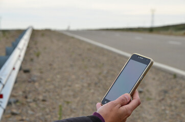 cell phone in woman's hand on deserted road