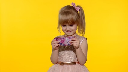 Technology for children. Little girl using smartphone. Portrait of child texting on smartphone. Kid enthusiastically playing games on mobile phone isolated on yellow background in studio.