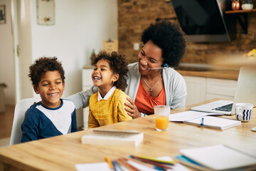 Happy black stay at home mother having fun with her kids while working at home.