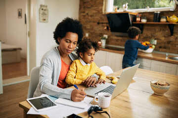 African American single mother with two kids working at home. - Powered by Adobe